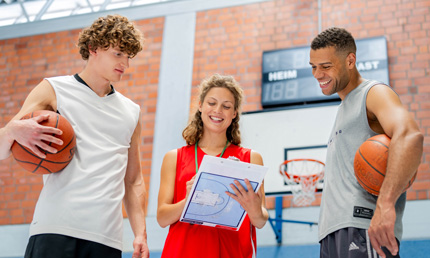 zwei Basektballspieler mit ihrer Trainerin bei Strategiebesprechung