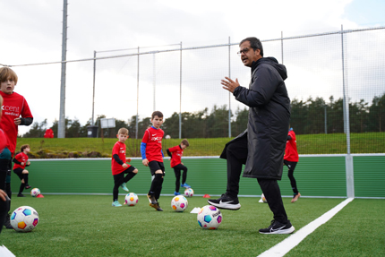 Fußballtrainer mit fußballsspielenden Jungs